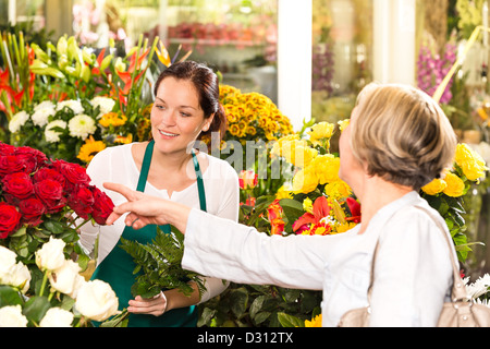 Les clients qui achètent des roses rouges fleuriste femmes travaillant Banque D'Images