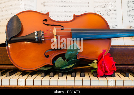 Une rose, violon, partitions et s'asseoir sur un piano en préparation pour une nuit de musique. Banque D'Images