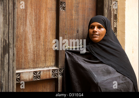 Le swahili femme debout à un traditionnel Zanzibar porte dans l'ancien fort, Lamu, archipel de Lamu, Kenya Banque D'Images