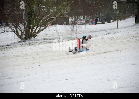 Un adulte et deux enfants sur un toboggan dans la neige. Banque D'Images