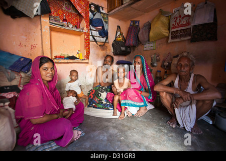 Sept membres d'une famille indienne de s'asseoir dans leur cabane de taudis en taudis Tehkhand habitation, Delhi, Inde. Banque D'Images