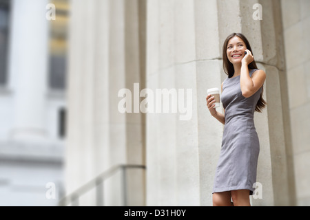 Asiatique multiraciale / Caucasian businesswoman talking on cell phone de boire du café en face de la cour Banque D'Images