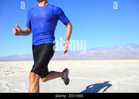 Jeune homme portant des vêtements de compression de l'athlète et le sprint en cours d'exécution à grande vitesse dans le désert Banque D'Images