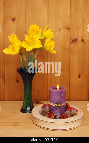 Brûler bougie Feng Shui avec pot-pourri et les jonquilles dans un vase contre un panneau de bois Banque D'Images