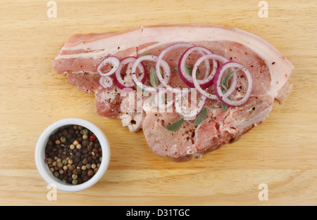 Habillée d'une côtelette de porc à la sauge et à l'oignon rouge avec poivre de poivre mélangés dans un ramequin sur une planche en bois Banque D'Images