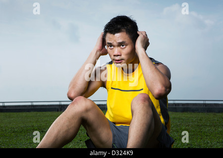 Chinese man performing crunch abdominale de l'exercice dans le parc Banque D'Images