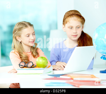 Portrait d'écolières smart assis en classe à l'avant de l'ordinateur portable Banque D'Images