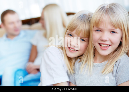 Portrait of happy twin girls looking at camera avec leurs parents derrière Banque D'Images