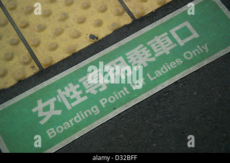 Ce panneau indique un point d'embarquement réservé aux femmes dans une gare JR West au Japon. Il reflète les efforts déployés pour offrir un environnement de voyage sûr et confortable aux passagers féminins pendant les heures de pointe, offrant un niveau supplémentaire de sécurité et de confidentialité dans les trains bondés. Banque D'Images