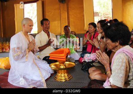 Un jeune moine novice lors de sa cérémonie d'initiation de recevoir la bénédiction et les prières de sa famille portant des vêtements blanc traditionnel. Banque D'Images