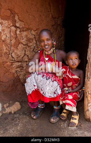 Masaï avec enfant assis à sa cabane dans la manyatta, Kenya Banque D'Images