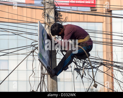 Un électricien travaille sur un enchevêtrement de fils électriques à Katmandou, au Népal. Banque D'Images