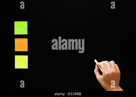 Part d'écrire quelque chose sur le tableau blanc avec trois couleurs différentes notes adhésives. Banque D'Images