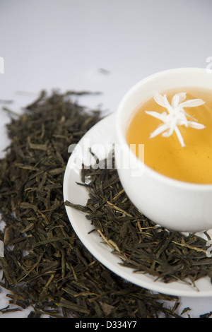 Le thé vert avec une fleur de Jasmin. Et les feuilles de thé dans une tasse. Banque D'Images
