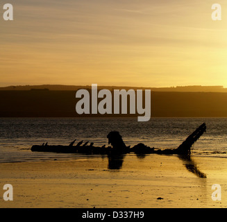 Le lever du soleil sur une ancienne épave d'un bateau de pêche à marée basse dans l'Estuaire de Cromarty, en Écosse. Banque D'Images