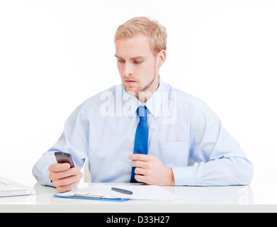 Jeune homme au bureau reading text message on mobile phone Banque D'Images