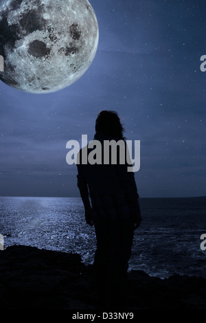 Une femme seule à bord malheureusement sur les falaises sous la pleine lune dans le comté de Clare Irlande Banque D'Images