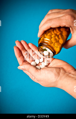 Woman pouring pills à partir d'un flacon de médicaments dans sa main Banque D'Images