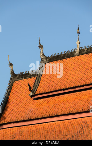 LUANG PRABANG, Laos - l'orange tuiles du toit à plusieurs niveaux de Wat Sensoukharam à Luang Prabang, Laos. Les points du toit sont décorées avec chofah, les représentations de Garuda, le mi-homme mi-oiseau que le dieu hindou Vishnu ride. Banque D'Images