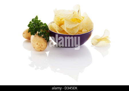 Croustilles de pommes de terre dans un petit bol violet avec des pommes de terre de côté sur fond blanc Banque D'Images