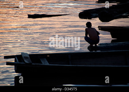 Un homme contre la lumière pendant un coucher de soleil sur l'amazone, au Pérou, pevas Banque D'Images