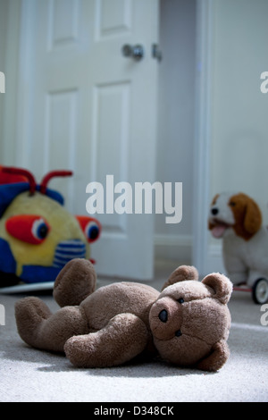 Ours en peluche brun portant sur un plancher de chambre à coucher de l'enfant. Banque D'Images