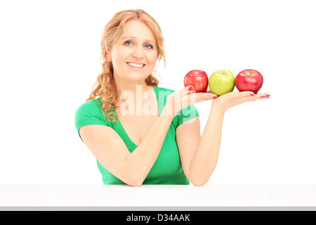 Young smiling woman sitting et la tenue de trois pommes isolé sur fond blanc Banque D'Images