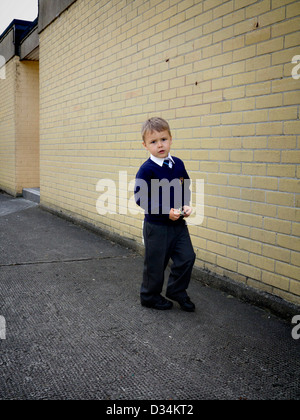 Un petit garçon dans la cour vêtu de son uniforme scolaire Banque D'Images