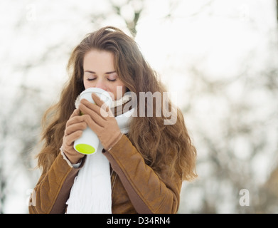 Jeune femme à boire le breuvage chaud dans winter park Banque D'Images