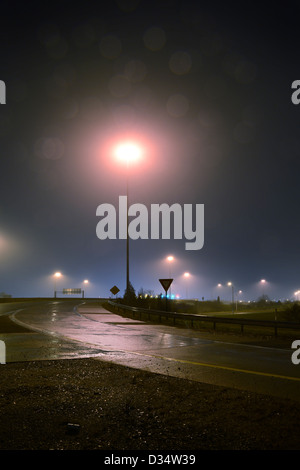 La bretelle pour l'autoroute de nuit dans le brouillard de pluie avec un lampadaire Banque D'Images