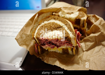 Le corned-beef sandwich reuben pour le déjeuner à côté de l'ordinateur portable de l'amérique du nord Banque D'Images