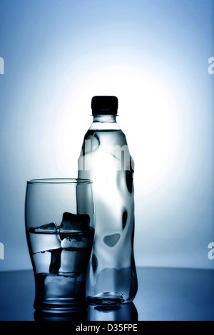 Verre d'eau minérale froide avec de la glace et une bouteille en plastique Banque D'Images