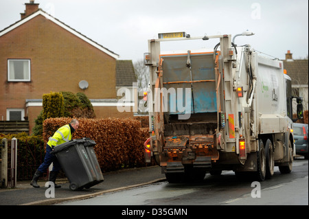 La collecte de déchets. Un homme se vide les poubelles wheelie bin des déchets, ordures, déchets en un chariot de compactage des déchets Banque D'Images