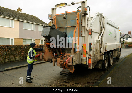 La collecte de déchets. Un homme se vide les poubelles wheelie bin des déchets, ordures, déchets en un chariot de compactage des déchets Banque D'Images