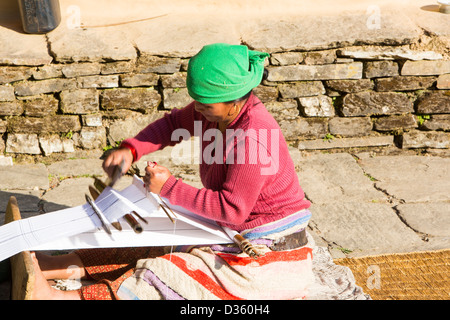 Une femme en costume traditionnel népalais tissu tissage sur un métier à tisser à la main au pied de l'Himalaya, au Népal. Banque D'Images