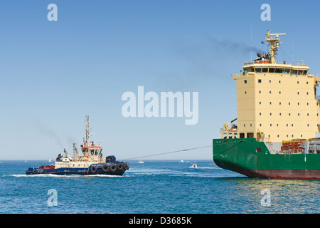 Un bateau remorqueur Svitzer au travail guidant le lourd Navire polyvalent, AAL Dampier, dans le port de Fremantle Banque D'Images