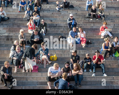 Les gens assis au soleil sur les marches de pierre à l'extérieur de la cathédrale d'Helsinki, Finlande. Banque D'Images