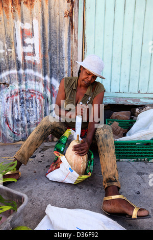 Femme assise dans les rues de Vieux Fort, St Lucia ouvrir une nouvelle courge et à l'aide d'un grand couteau Banque D'Images