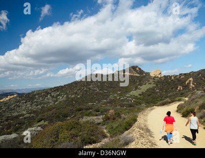 Les femmes randonnées route menant à Eagle Rock, vu dans la distance, à Topanga State Park à Topanga, California Banque D'Images