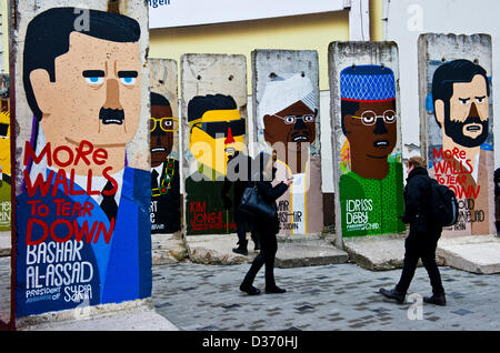 Berlin, Allemagne. 11 février 2013. Les touristes se tiennent près de morceaux de l'ancien mur de Berlin montrant le président de la Syrie Bachar El Assad (L-R), le Président du Zimbabwe Robert Mugabe, ancien dictateur nord-coréen Kim Jong-il, Président du Soudan Ular al-Baschir, Président du Tchad Idriss Deby et le président d'Iran Mahmoud Ahmadinejad avec l'écriture "oreWalls à abattre' à Berlin, Allemagne, 11 février 2013. Photo : Nicolas Armer/Alamy Live News Banque D'Images