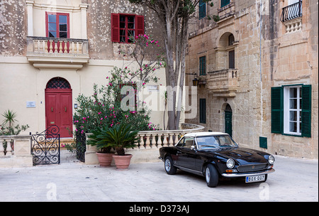 Un classique noir Fiat 124 Sport Spider motor voiture garée à l'extérieur d'une maison dans la ville médiévale fortifiée de Mdina, Malte. Banque D'Images