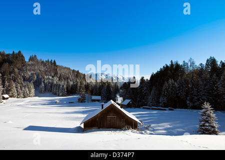 Paysage d'hiver ensoleillé Rural occupé avec des cabanes en bois dans les montagnes Banque D'Images