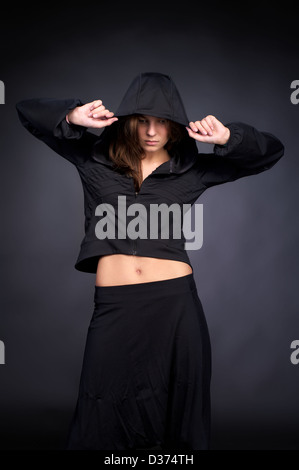 Belle jeune femme de style hip-hop avec un capuchon sur la tête contre le mur noir Banque D'Images