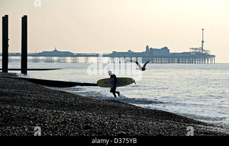 Brighton Sussex UK. 12 février 2013 - Surfer porte son bord jusqu'Brighton Beach tôt le matin en hiver Banque D'Images