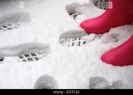 Des traces de pas dans la neige et paire de bottes Rose Banque D'Images