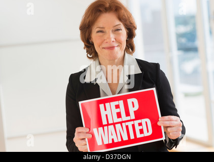 USA, New Jersey, Jersey City, Portrait of businesswoman holding help wanted sign Banque D'Images