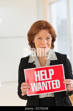 USA, New Jersey, Jersey City, Portrait of businesswoman holding help wanted sign Banque D'Images