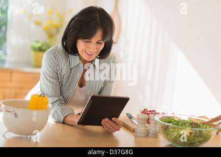 USA, New Jersey, Jersey City, Senior woman holding digital tablet while preparing salad Banque D'Images