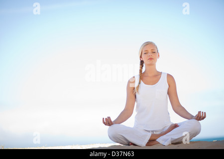 Woman meditating on beach Banque D'Images