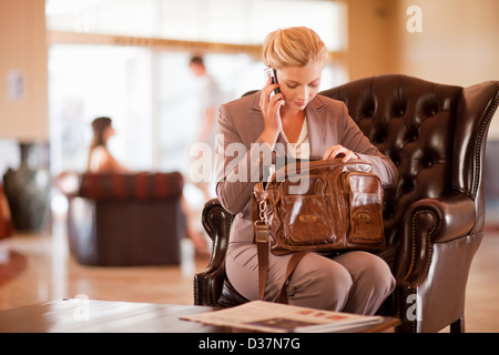 Businesswoman on cell phone in lobby Banque D'Images